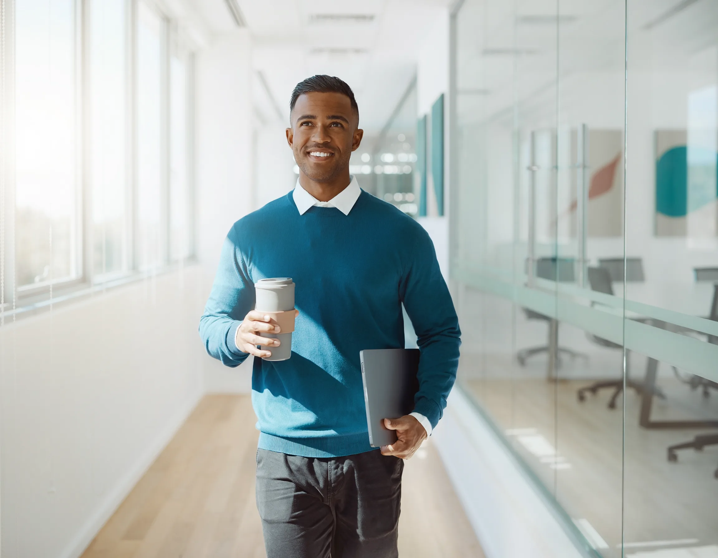 Junger Praktikant mit Laptop im hellen Büroflur — Praktikum bei ARWA