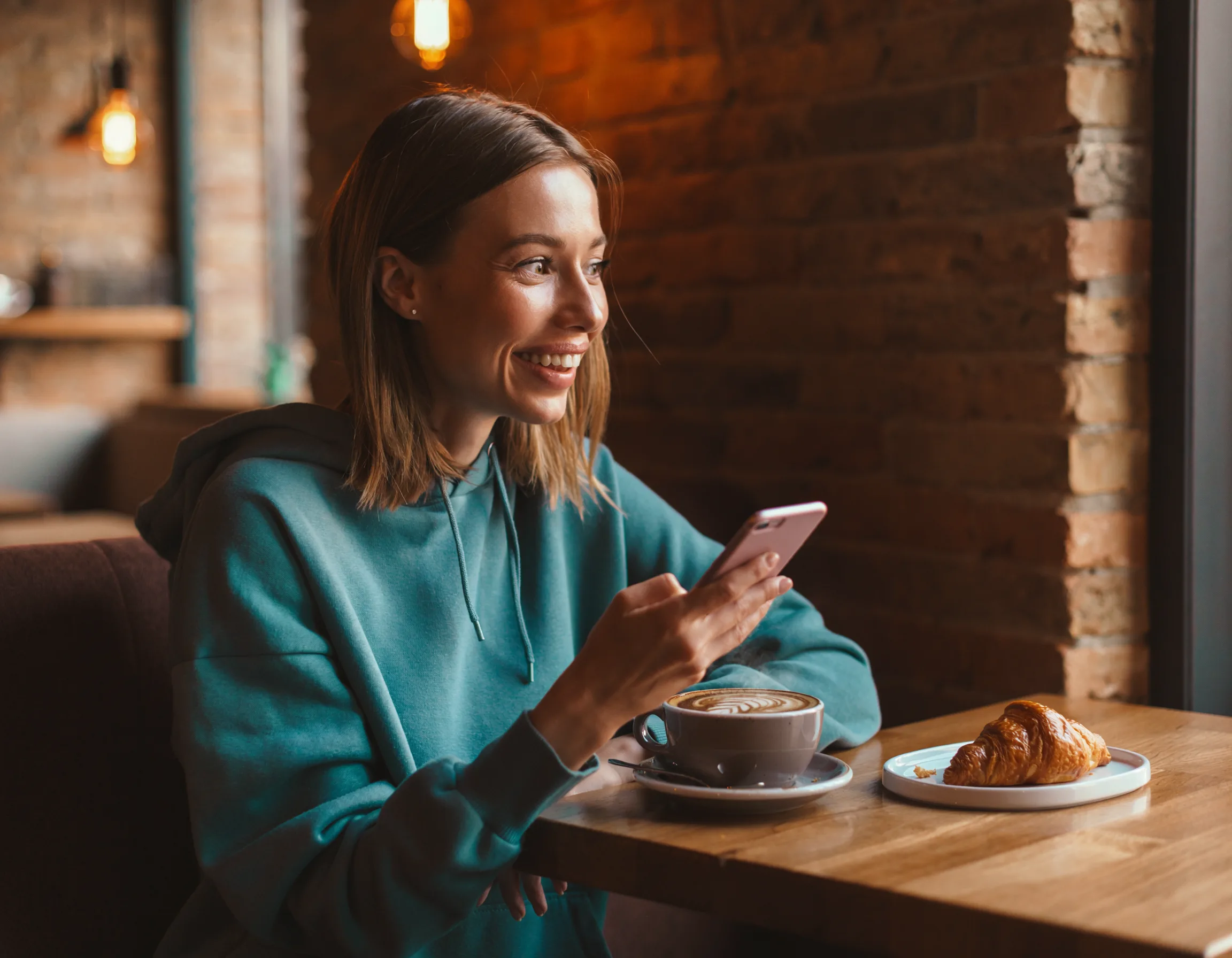 Junge Frau erhält Job-Benachrichtigung auf dem Smartphone im Café — ARWA Job-Newsletter