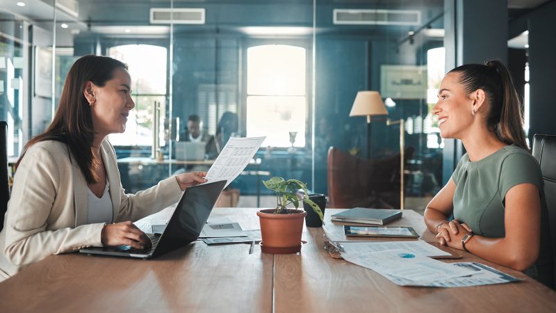 Zwei Frauen im GesprÃ¤ch in einem modernen BÃ¼ro â€“ symbolisiert persÃ¶nliche FÃ¤higkeiten wie Kommunikation und Teamarbeit.