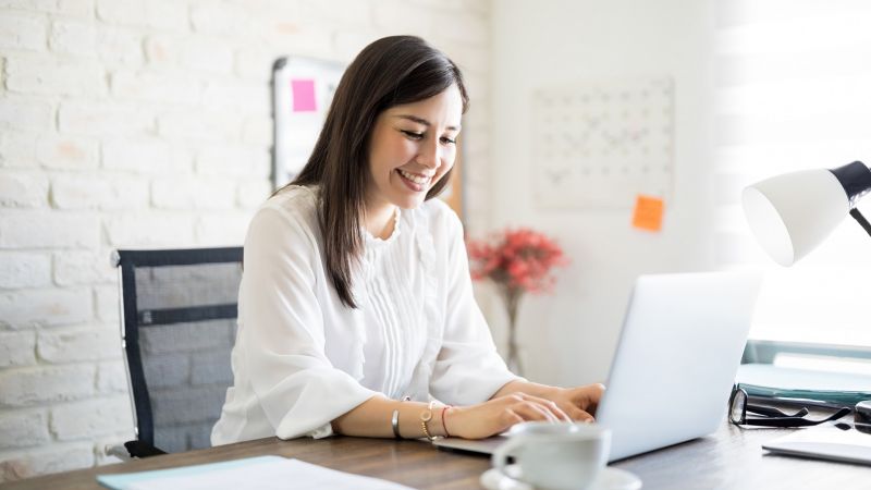 LÃ¤chelnde Person arbeitet konzentriert am Laptop im BÃ¼ro und zeigt Eigenverantwortung bei der Arbeit.