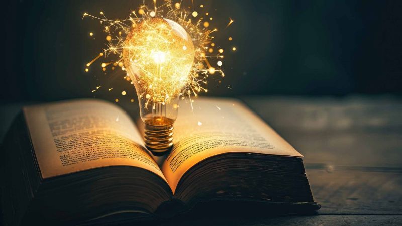 Eine leuchtende GlÃ¼hbirne mit Funken Ã¼ber einem aufgeschlagenen Buch, die kreatives Lernen symbolisiert.