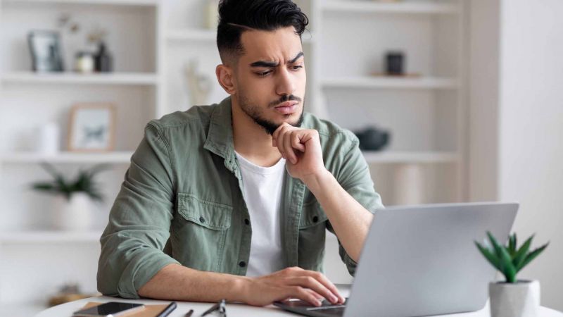 Nachdenklicher Mann sitzt vor einem Laptop und analysiert. Symbolisiert Reflektion, ProblemlÃ¶sung und die Auseinandersetzung mit Herausforderungen.