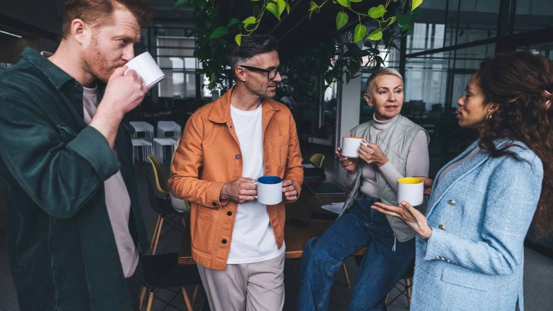 Gruppe von Menschen im GesprÃ¤ch mit Kaffeetassen in der Hand, symbolisiert die soziale Interaktion und die Herausforderung von hochsensiblen Personen im Umgang mit Gruppen.