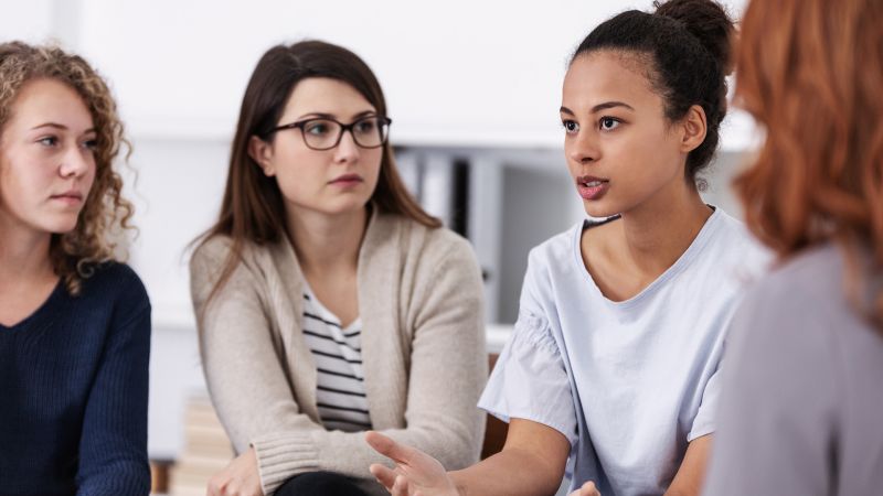 Gruppe von Frauen in einer GesprÃ¤chsrunde, eine Frau spricht aktiv und gestikuliert