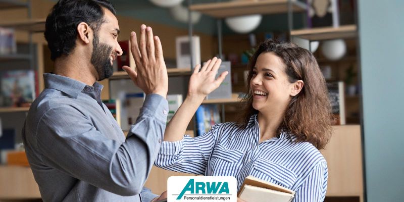 Zwei Kollegen geben sich im Büro ein High-Five – Symbol für ein positives Arbeitsklima und Teamgeist.