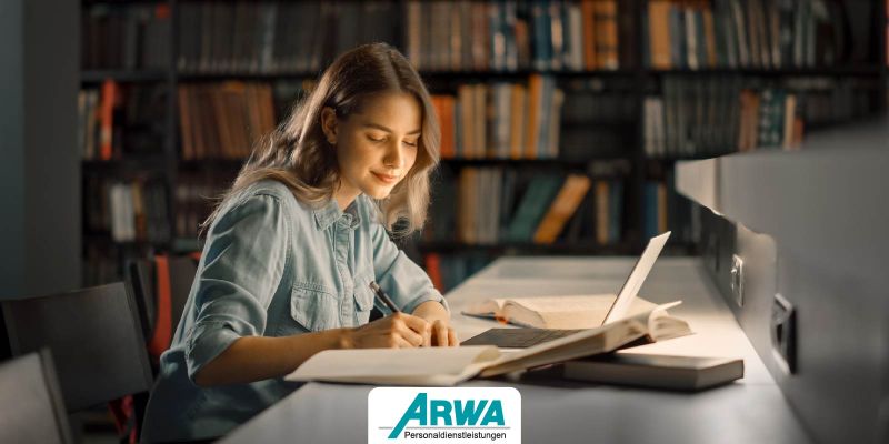 Junge Frau in einer Bibliothek beim Lernen, umgeben von Büchern und einem Laptop – Symbol für schnelle Auffassungsgabe und Wissensaneignung. ARWA Personaldienstleistungen Logo im Vordergrund.