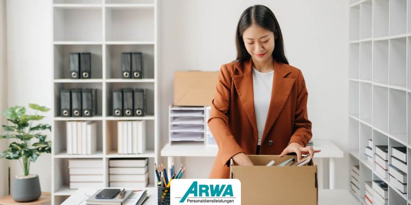 Frau in einem Büro packt eine Kiste mit Büromaterialien, symbolisiert den beruflichen Neustart als Quereinsteiger.